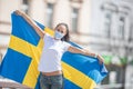 Beautiful smiling Swedish girl holds a flag while wearing a protective face mask outdoors Royalty Free Stock Photo