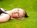 Beautiful smiling teenage girl lying on her back in the green gr Royalty Free Stock Photo