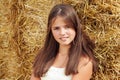 Beautiful smiling teenage girl sitting near a hay bale Royalty Free Stock Photo