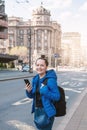 Beautiful smiling tourist woman with mobile phone and backpack standing near road in the Belgrade city, Serbia Royalty Free Stock Photo