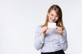 A beautiful smiling woman in a blue shirt with glasses holds and shows a blank card or company business card. Promotion concept Royalty Free Stock Photo