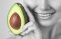 Beautiful smiling woman with clean skin holds ripe avocado near the face. Cosmetology skin care