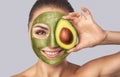 Beautiful smiling woman with clean skin holds ripe avocado near the face. She made a natural avocado mask. Cosmetology skin care