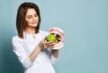 Beautiful smiling woman dentist or doctor orthodontist holding artificial jaw and fresh green apple and showing healthy teeth