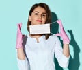 Beautiful smiling woman dentist or doctor orthodontist in uniform and gloves putting medical mask on face