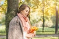 Beautiful smiling woman dreams and holding autumn yellow maple leaf outdoors. Romantic girl in fall park Royalty Free Stock Photo