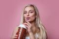 Beautiful smiling blond woman drinking ice cream cocktail over pink background Royalty Free Stock Photo