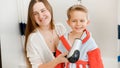 Beautiful smiling woman drying hair and blowing hot air with hairdryer on her little son after washing in bath. Concept Royalty Free Stock Photo