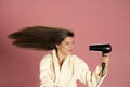 Beautiful smiling woman drying her long hair with electric fan Royalty Free Stock Photo