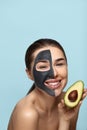 Beautiful of smiling woman with facial mask on her face holding half an avocado in front of her face. Beauty Skin care Royalty Free Stock Photo