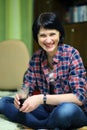 A beautiful smiling woman with a glass in her hand crosses her legs.