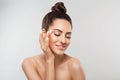 Beautiful smiling woman with healthy smooth facial clean skin applying cosmetic cream and touch own face. Model with  Beauty face. Royalty Free Stock Photo