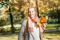 Beautiful smiling woman holding autumn yellow maple leaf outdoors. Romantic girl in fall park Royalty Free Stock Photo