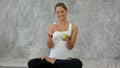 Beautiful smiling woman holding green apple, jungle with it, sitting in lotus pose Royalty Free Stock Photo