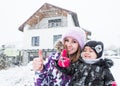 Beautiful smiling woman with little child thumbs up on big cottage background Royalty Free Stock Photo