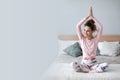 Beautiful smiling woman in lotus pose on bed practicing yoga at home with copy space Royalty Free Stock Photo