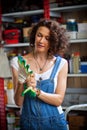 smiling woman mechanic in blue denim overalls tries to hand protective gloves