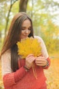 Beautiful smiling woman outdoor portrait, fresh skin and healthy smile, hold maple leaves bouqet front of face