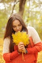 Beautiful smiling woman outdoor portrait, fresh skin and healthy smile, hold maple leaves bouqet front of face