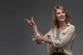 Beautiful smiling woman pointing with both hands to copyspace on her left hand side against a grey studio background Royalty Free Stock Photo