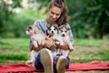 A beautiful smiling woman with a ponytail and wearing a striped shirt is holding three sweet husky puppies on the lawn Royalty Free Stock Photo