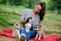 A beautiful smiling woman with a ponytail and wearing a striped shirt is holding three sweet husky puppies while sitting Royalty Free Stock Photo