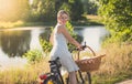 Beautiful smiling young woman posing on vintage bicycle in field at susnet