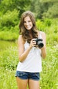 Beautiful smiling woman is professional photographer with DSLR camera and taking pictures outdoors in summer nature Royalty Free Stock Photo