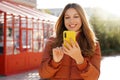 Beautiful smiling woman in puffer jacket holding smartphone on winter time