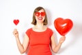 Beautiful smiling woman in red sunglasses holding in her hands a heart balloon and a heart lollipop. Royalty Free Stock Photo