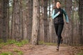 Beautiful Smiling Woman Running on the Forest Trail at Cold Autumn Evening. Sport and Active Lifestyle.