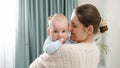 Beautiful smiling woman stroking her little baby son at bedroom. Concept of family happiness and child development Royalty Free Stock Photo