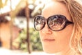 Beautiful smiling woman sunglasses portrait on beach with sunlight on woman face and reflection of beach palm trees in sunglasses Royalty Free Stock Photo