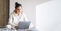 Beautiful smiling woman teenager girl student freelancer with dark long hair in casual using laptop sitting on bed at home, banner Royalty Free Stock Photo