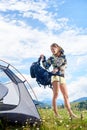 Woman tourist hiking in mountain trail, enjoying summer sunny morning in mountains near tent Royalty Free Stock Photo