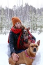 Beautiful smiling woman is on a walk with her two dogs in winter coniferous forest Royalty Free Stock Photo