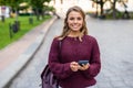 Beautiful smiling woman walking on crowded city street from work texting on mobile phone Royalty Free Stock Photo