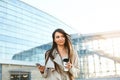 Beautiful smiling woman walking on near office from work with coffee cup and texting on mobile phone Royalty Free Stock Photo