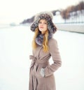 Beautiful smiling woman wearing a coat and hat over snow in winter Royalty Free Stock Photo