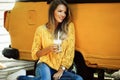 Beautiful smiling woman is wearing yellow sweater drinking coffee latte near old retro bus Royalty Free Stock Photo