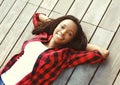 Beautiful smiling young african woman relaxed on wooden floor with hands behind head, wearing a red checkered shirt Royalty Free Stock Photo