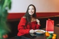 Beautiful smiling young asian woman in red clothes eating asian food in the chinese vietnamese restaurant