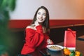 Beautiful smiling young asian woman in red clothes eating asian food in the chinese vietnamese restaurant