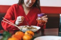 Beautiful smiling young asian woman in red clothes eating noodles with bamboo chopsticks in the chinese vietnamese restaurant Royalty Free Stock Photo