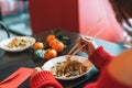 Beautiful smiling young asian woman in red clothes with friend eating noodles with bamboo chopsticks in the chinese vietnamese Royalty Free Stock Photo