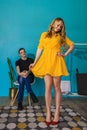 Beautiful smiling young blonde woman in retro yellow dress shows the outfit to her boyfriend.