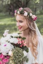 beautiful smiling young bride in floral wreath and veil holding bouquet Royalty Free Stock Photo