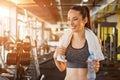 Beautiful smiling young fit woman with towel and water bottle preparing for sports training in gym Royalty Free Stock Photo