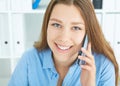 Beautiful smiling young Caucasian girl talking on the mobile phone in the office. Royalty Free Stock Photo