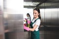 beautiful smiling young janitor cleaning elevator with detergent and rag Royalty Free Stock Photo